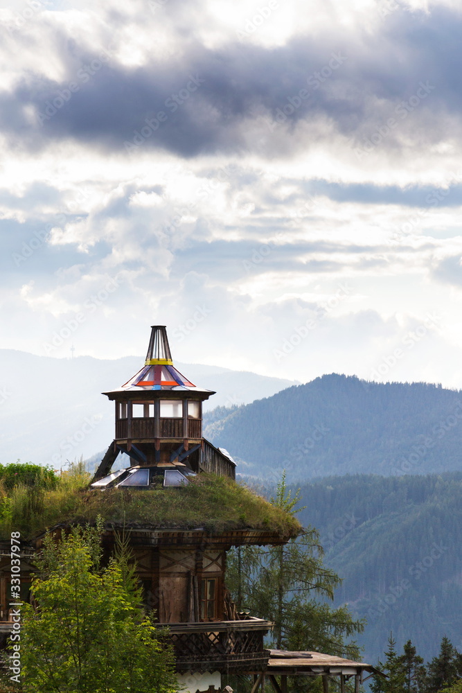 Obraz premium Beautiful sunset with dramatic clouds over Dachstein mountains, wooden lookout with green sod roof in foreground, Northern Limestone Alps, Schladming, romantic love peaceful meditation concept