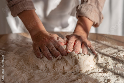 Close-up of the hands of a woman kneading bread dough