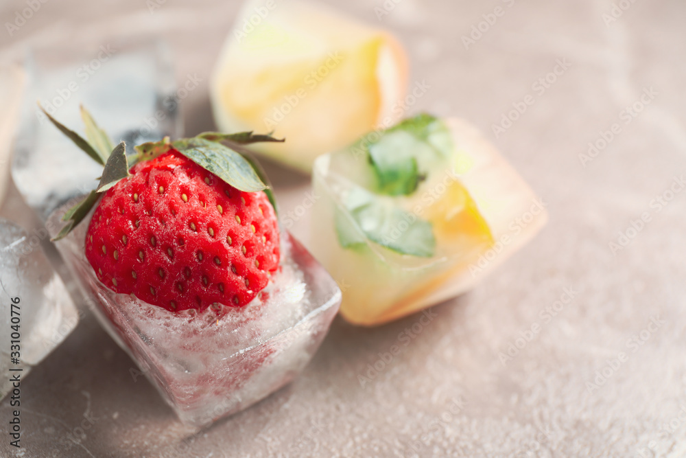 Ice cubes with different berries and mint on grey table, closeup Ice cubes with different berries and mint on grey table, closeup