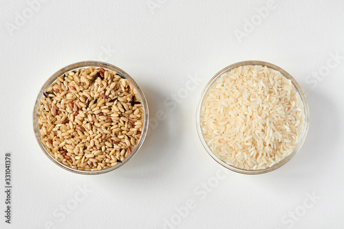 Raw brown rice and white rice in a transparent glass plate on white background. Problem of choice. Closeup, top view