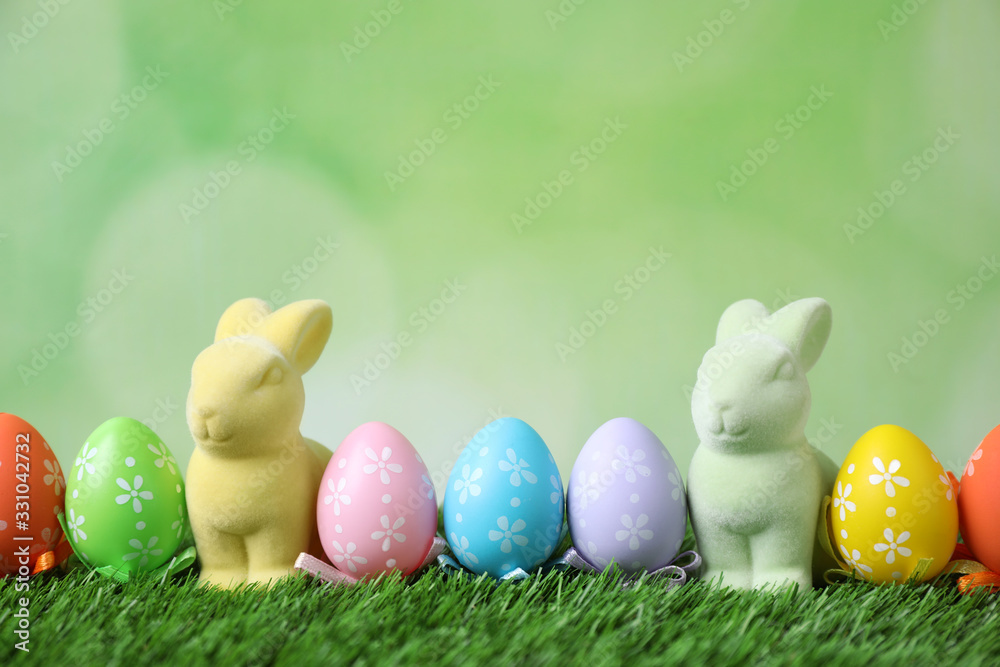 Easter bunnies and painted eggs on green grass Easter bunnies and painted eggs on green grass