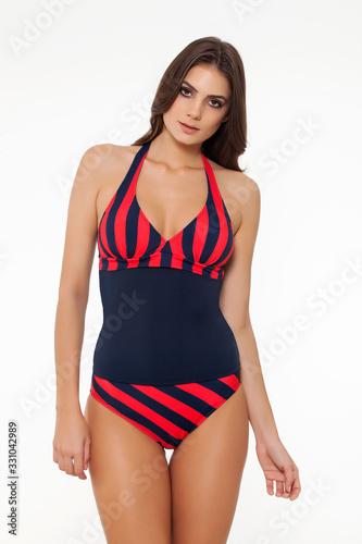 beautiful girl posing in stylish detailed coral and navy blue swimsuit on white background.
