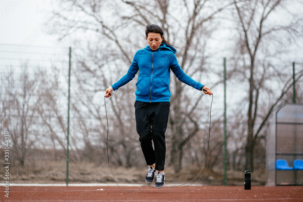 A young woman is engaged in jumping rope. A young woman is engaged in jumping rope.