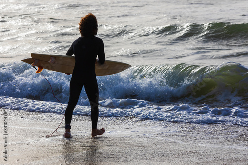 A surfer with a board enters the water
