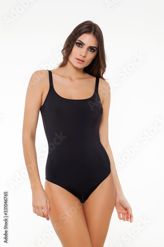 beautiful girl posing in stylish black swimsuit on white background.