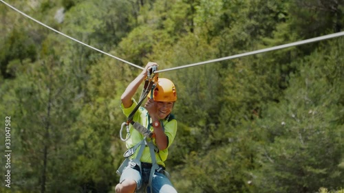 Zip line in mountains, a cable between rocks. Moving with zipline at via ferrata. Small boy use zip line path after hiking to quickly move down to the next mountain. He is happy and exited.