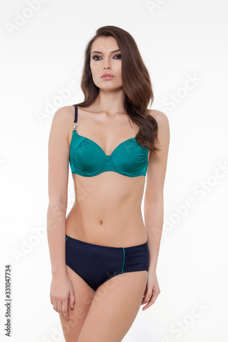 beautiful girl posing in stylish detailed chic navy blue and green bikini on white background.