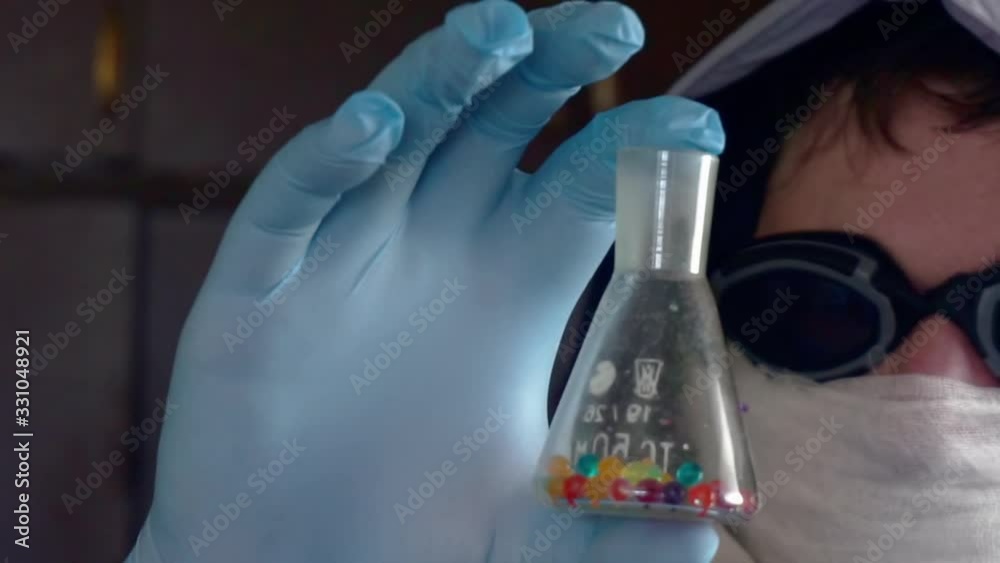 researcher in a protective uniform holds a dirty glass tube researcher in a protective uniform holds a dirty glass tube