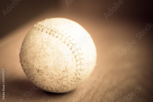 Close up of a Well used softball in sepia