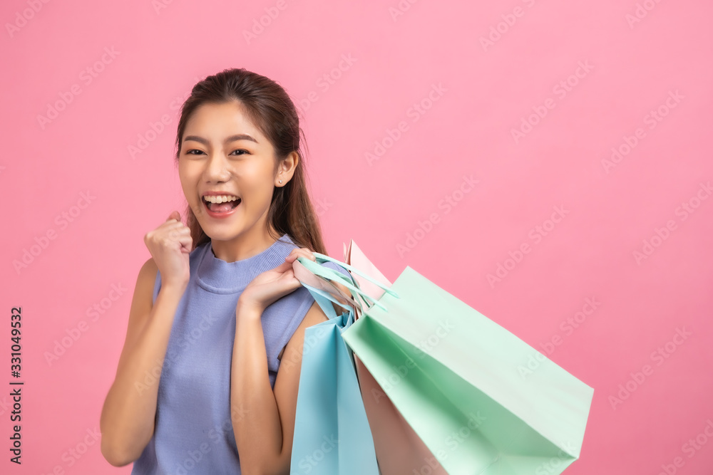 Asian pretty young woman sitting on pink pastel background. She smiling and happy .She hold shopping bags. she nice-looking lovely attractive shine . Asian pretty young woman sitting on pink pastel background. She smiling and happy .She hold shopping bags. she nice-looking lovely attractive shine .