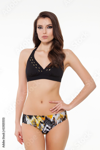 beautiful girl posing in stylish detailed black bikini on white background.