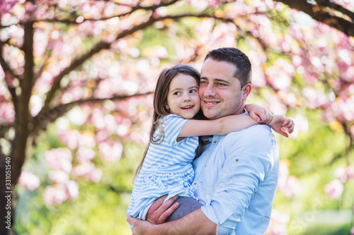 Young father holding small daughter outside in spring nature. © Halfpoint