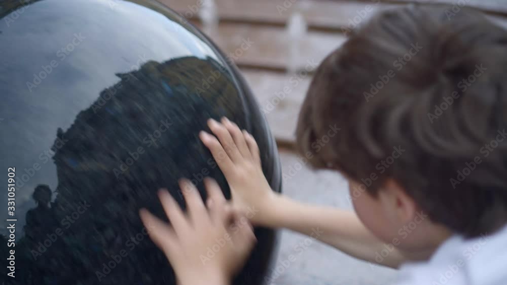 charming caucasian boy having fun with fountain shot during summer time