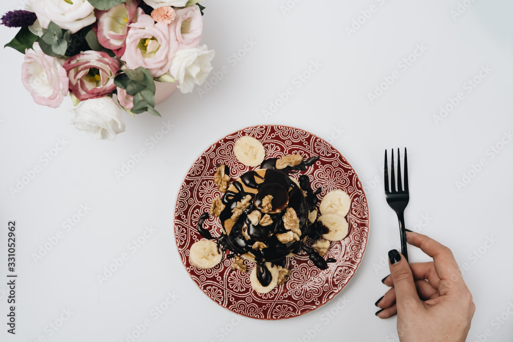 Fototapeta premium Stack of delicious homemade pancakes with chocolate topping, walnuts and sliced bananas