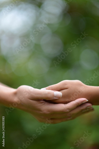 Daughter and mother holding hands close up