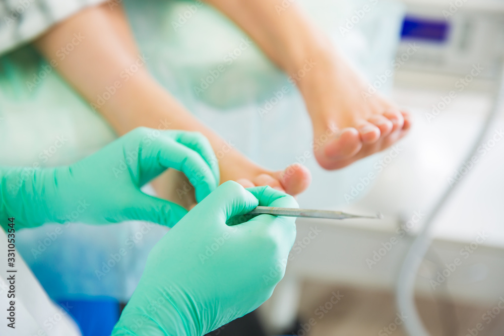 Woman sitting in chair, having foot treatment in spa salon. Professional medical pedicure specialist in protective mask using special electric lathe and tools. Close-up feet Woman sitting in chair, having foot treatment in spa salon. Professional medical pedicure specialist in protective mask using special electric lathe and tools. Close-up feet