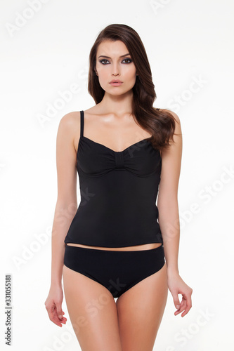 beautiful girl posing in stylish detailed black tankini on white background.