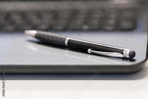 Close-up shot at a pen resting on top of a laptop.