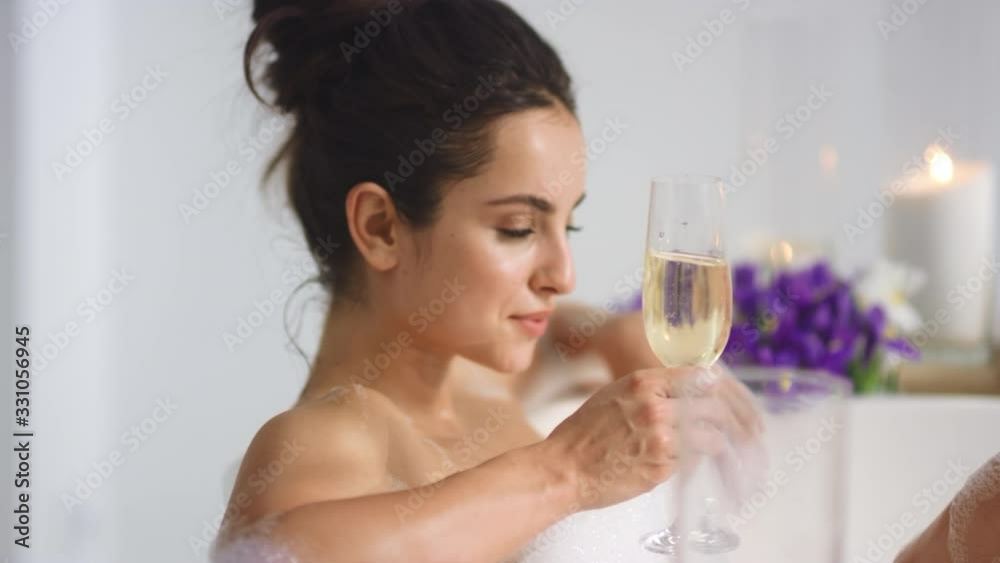 Sexy girl relaxing with wine in bathtub. Woman holding champagne in bath Sexy girl relaxing with wine in bathtub. Woman holding champagne in bath