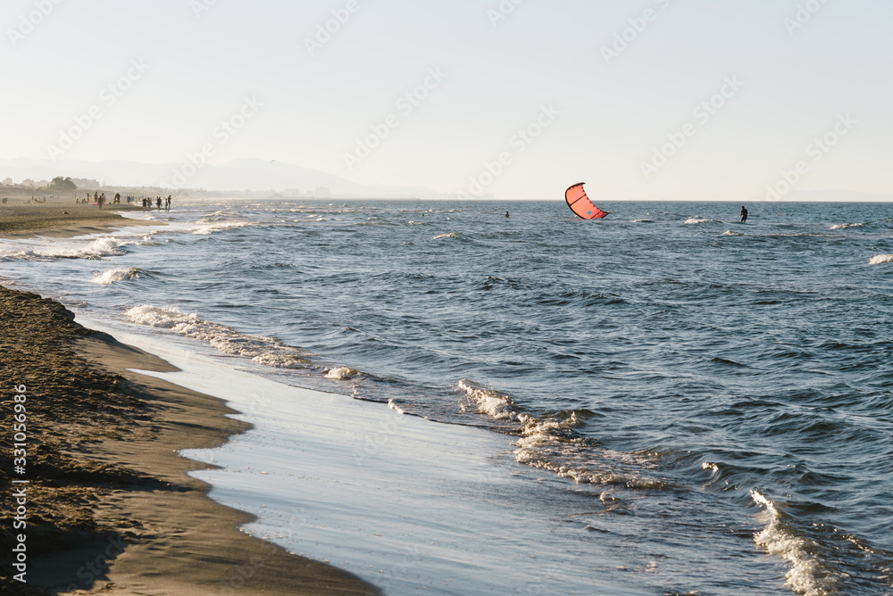 Summer afternoon on the beach with people doing kitesurf in Mediterranean Sea
