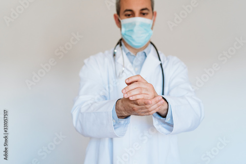 caucasian doctor wearing protective mask and gloves indoors. Using an alcohol gel or antibacterial disinfectant. Hygiene and corona virus concept