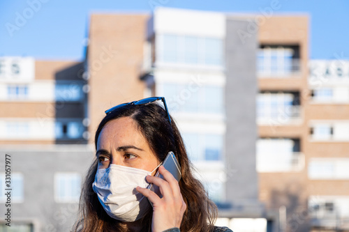 young woman with a respirator on the street with her smart phone