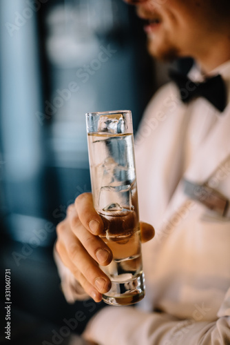 Bartender holding on his hand gin and tonic cocktail in a highball glass. Smooth image with shallow depth of field. 