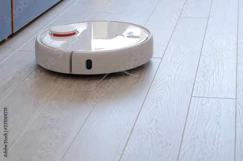 Robotic vacuum cleaner on laminate wood floor.