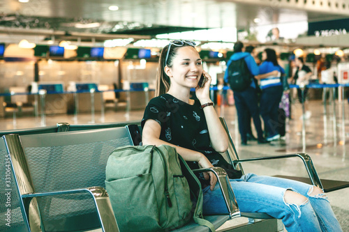 Girl tourist or student talking on a cell phone or mobile phone at the airport while waiting for a flight.