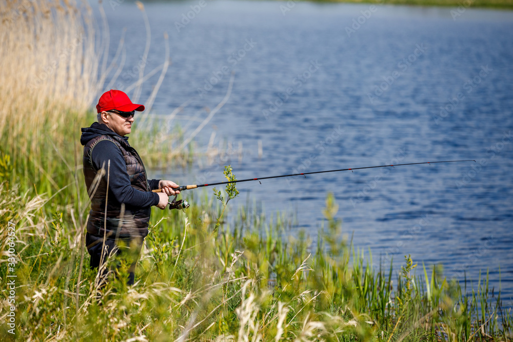 Elderly man enjoys fishing by the river in the summer. Elderly man enjoys fishing by the river in the summer.