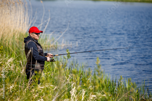 Elderly man enjoys fishing by the river in the summer.