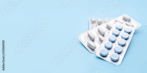 Photos Pills in blister packs on blue background. Medicine concept.