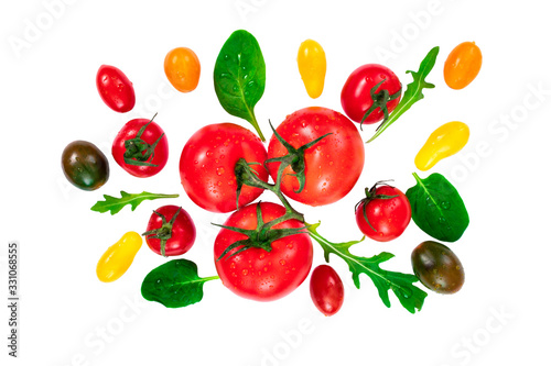 Various colorful tomatoes and basil leaves with drops of water isolated on white background. Top view, flat lay
