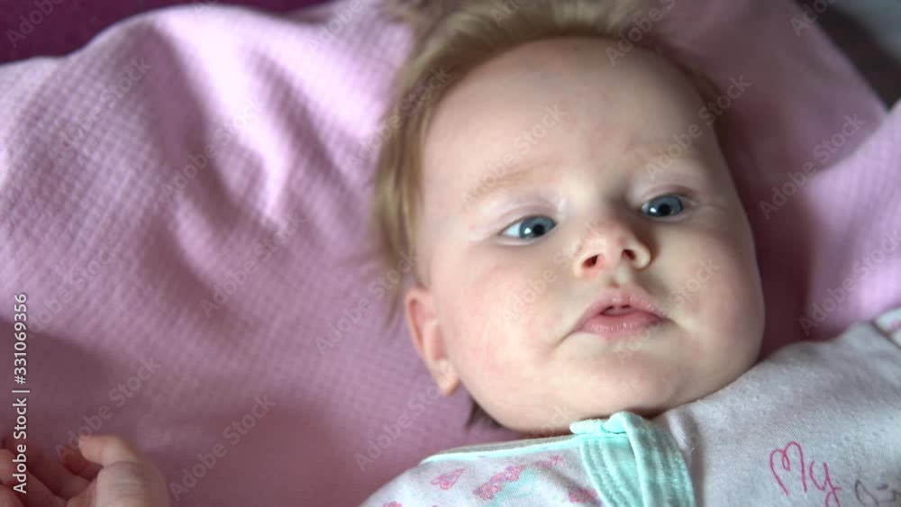 The baby is lying on the bed and smiling. Face close up. The baby is lying on the bed and smiling. Face close up.