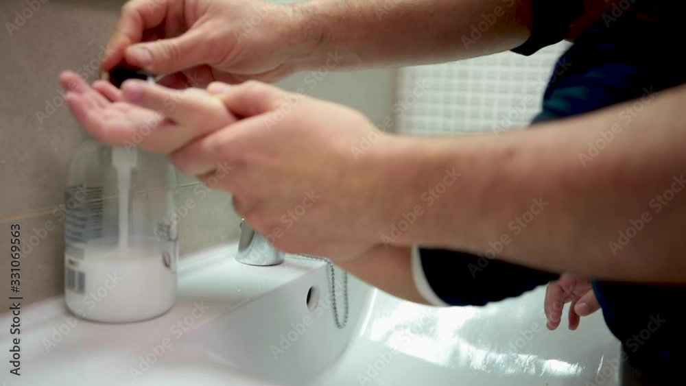 A father helps his five-year-old daughter wash their hands with soap and water in the bathroom to ward off infections A father helps his five-year-old daughter wash their hands with soap and water in the bathroom to ward off infections