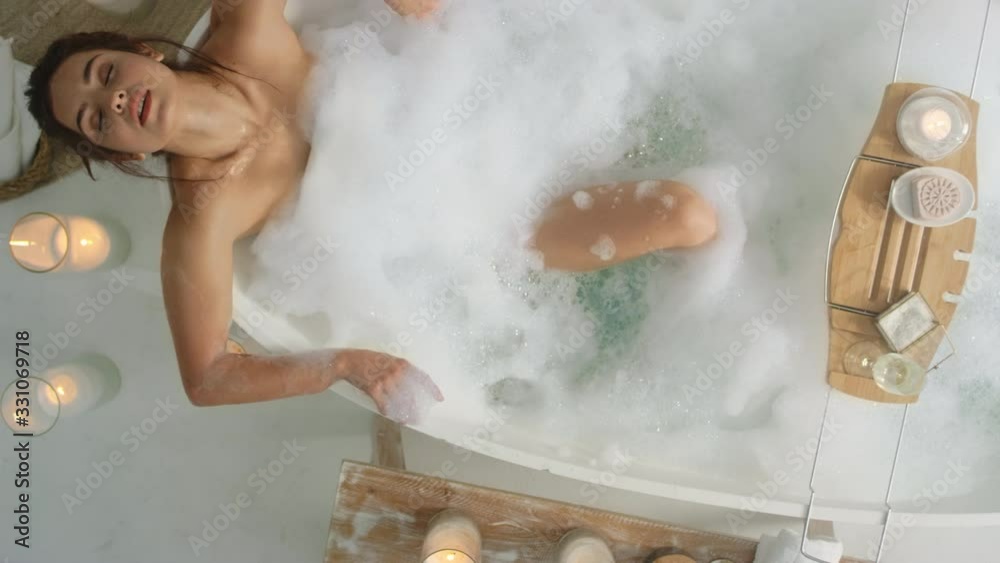 Sexy woman bathing at home. Relaxed girl lying in bath with foam.