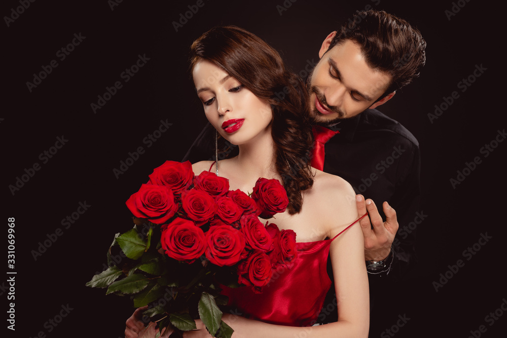 Elegant man taking off dress from girlfriend with red roses isolated on black Elegant man taking off dress from girlfriend with red roses isolated on black
