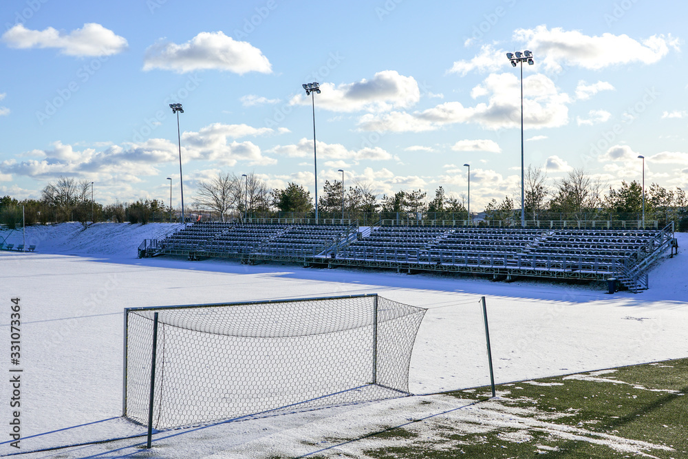 empty football field in winter, covered with snow empty football field in winter, covered with snow