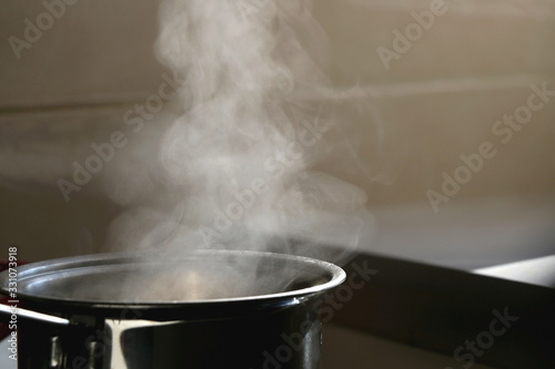 Cooking pot with steam on a kitchen stove. Selective focus.