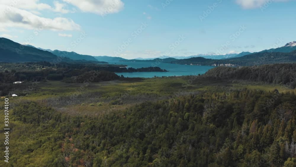 Aerial view of wetlands, floodplain near a lake and forest with mountains in the background. Villa la Angostura, Patagonia Argentina. Drone moving backwards. Aerial view of wetlands, floodplain near a lake and forest with mountains in the background. Villa la Angostura, Patagonia Argentina. Drone moving backwards.
