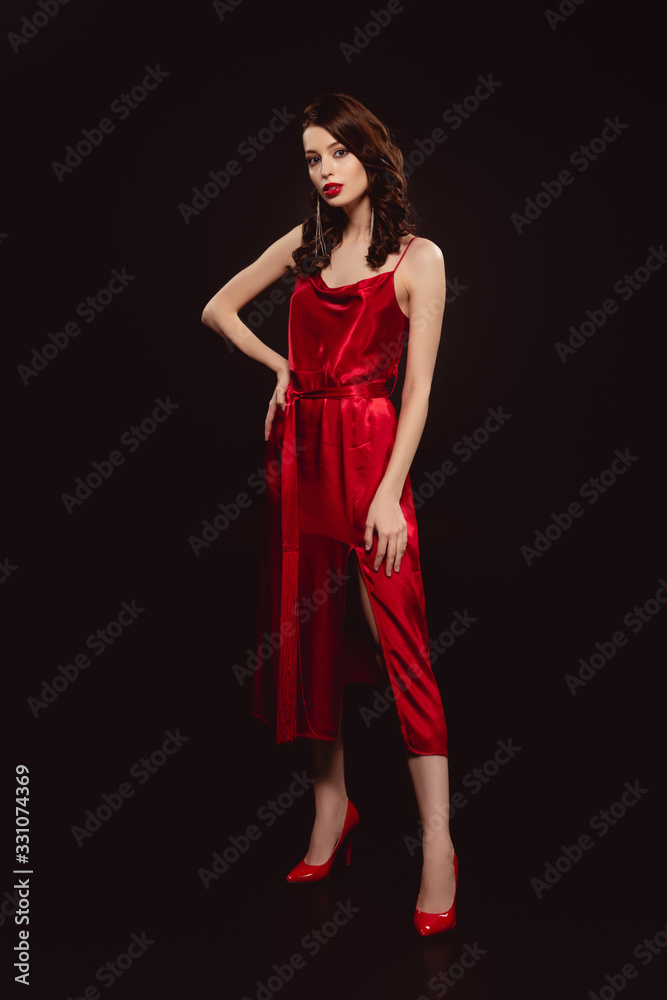 Full length of beautiful woman in red dress looking at camera isolated on black Full length of beautiful woman in red dress looking at camera isolated on black