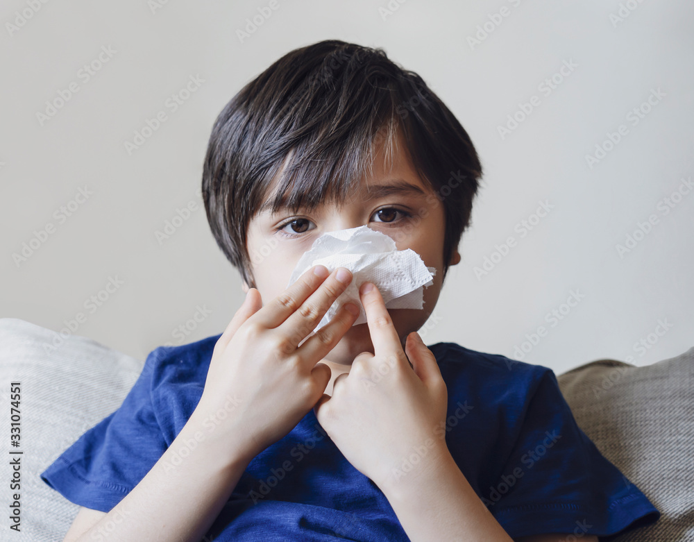 Unhealthy kid blowing nose into tissue, Child suffering from running nose or sneezing , A boy catches a cold when season change, childhood wiping nose with tissue Unhealthy kid blowing nose into tissue, Child suffering from running nose or sneezing , A boy catches a cold when season change, childhood wiping nose with tissue