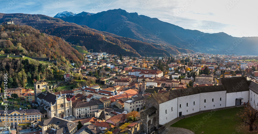 Stunning aerial panorama view of Bellinzona old town in beautiful sunlight from top of Castelgrande Castle with Swiss Alps and blue sky cloud in background, on sunny autumn day, Ticino, Switzerland