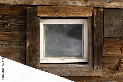 small wooden window on a background of an old wooden wall.