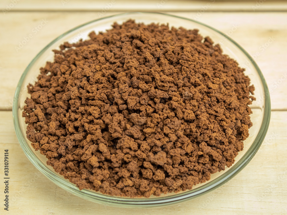 Granulated coffee in a glass plate on a wooden background Granulated coffee in a glass plate on a wooden background