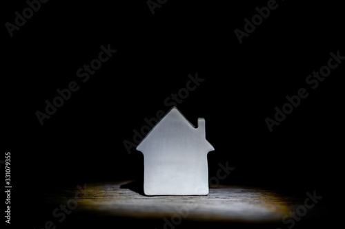 Home with love warm and friendly environment on spotlight. Wooden housing model for real estate planning with hand holding house model