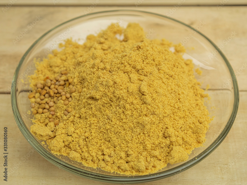 Seasoning mustard powder in a glass plate on a wooden background Seasoning mustard powder in a glass plate on a wooden background