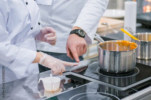 Chef shows how to use electric stove at cuisine of restaurant. Professional cooking  training  education  learning  instruction  catering  cookery  gastronomy and food concept