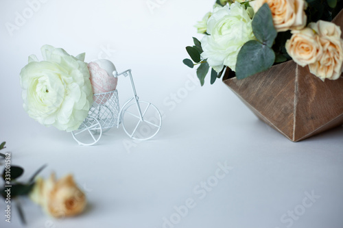 Rustic Easter composition with egg decorated ribbon lace  white little bicycle with fabulous ranunculus and flowers composition. Side view.