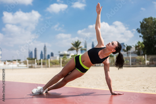 Fitness woman strength training her body core muscles with yoga pose. Athlete planking on one arm doing side plank and hip lift.